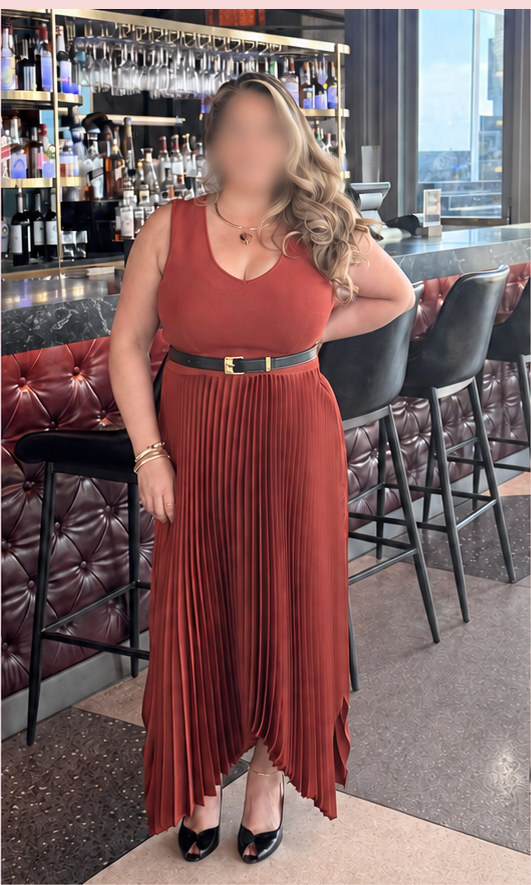 The same client after her color analysis and wardrobe edit, wearing a terracotta pleated midi dress with a fitted belt